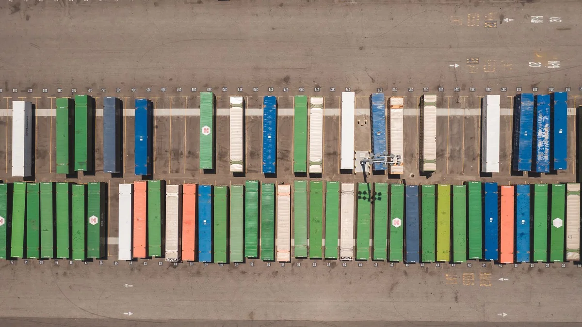Aerial view of cargo containers arranged at an international shipping terminal.