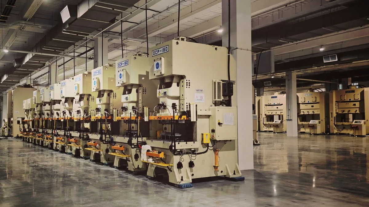 Rows of industrial stamping presses on a modern factory production floor.